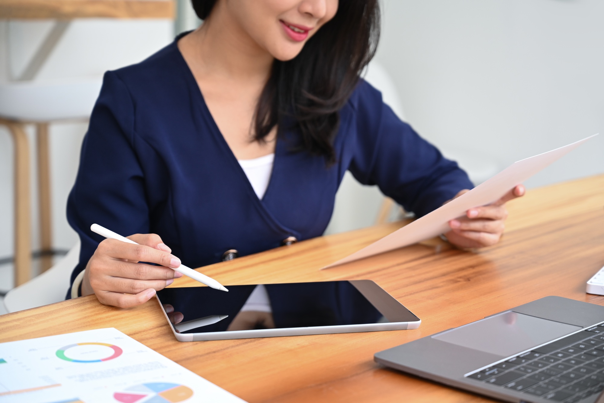 Female investor holding document ad searching online information on digital tablet.
