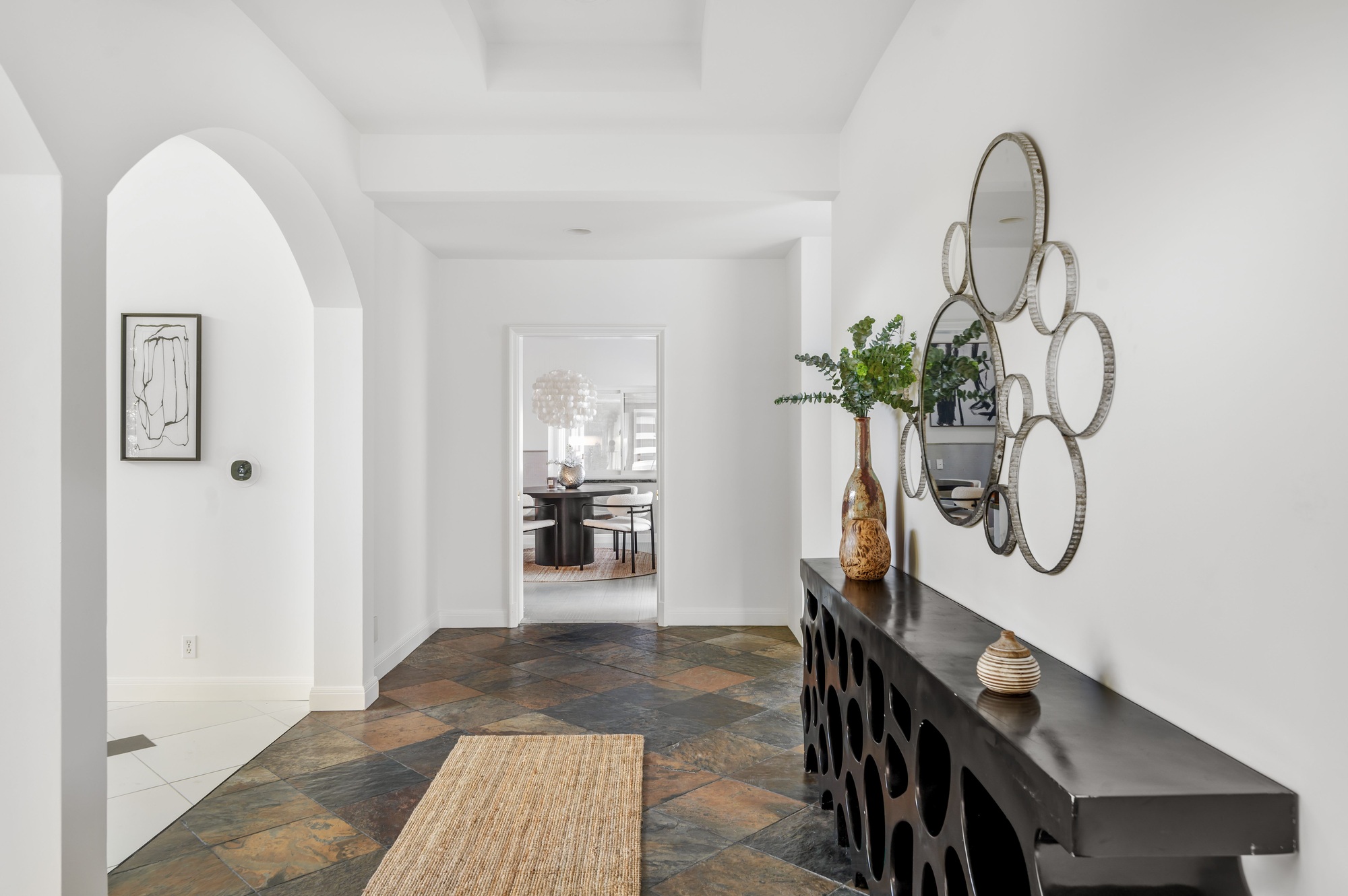 Modern hallway with decorative mirror and console table, leading to a stylish dining room